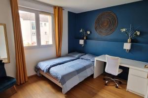 1 dormitorio con cama, escritorio y ventana en Maison cosy-JO24 à Voisins-le-Bx, en Voisins-le-Bretonneux