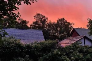 un ciel rouge sur les toits de maisons arborées dans l'établissement Shrigley cottage, quirky & quiet, à Macclesfield