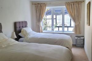 two beds in a bedroom with a window at Shrigley cottage, quirky & quiet in Macclesfield