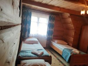 two twin beds in a room with a window at Dom Wczasowy u Gruszki in Dzianisz