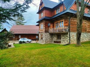 a large wooden house with a car parked in the yard at Dom Wczasowy u Gruszki in Dzianisz