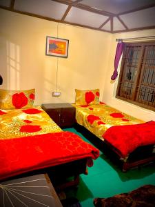 two beds in a room with red and yellow sheets at The Kashi Baba Homestay in Dharamshala