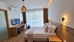 Dormitorio con cama, escritorio y TV en Waterside SPA Hotel en Ognyanovo