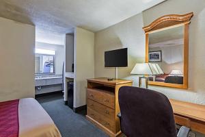 a hotel room with a bed and a desk with a mirror at Eco-Inn Suites Baytown in Baytown
