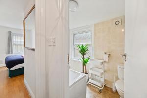 a bathroom with a tub and a toilet and a sink at Cosy Urban Oasis 2 Bedroom Flat in Tottenham ( Sleeps 5 People ) in London