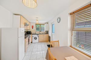 a kitchen with a table and a white refrigerator at Cosy Urban Oasis 2 Bedroom Flat in Tottenham ( Sleeps 5 People ) in London