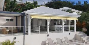 a white house with white chairs and a porch at Villa Blue Marine in Deshaies