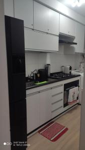 cocina con armarios blancos y fogones en Apt 2 qtos, prox. ao Rio centro, Jun, e P. Olimpic en Río de Janeiro