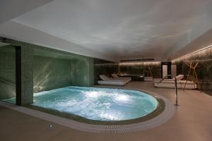 une baignoire jacuzzi dans une chambre avec un canapé et des chaises dans l'établissement Hotel Afonso V & SPA, à Aveiro