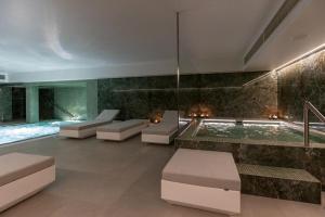 ein Zimmer mit Swimmingpool und weißen Möbeln und einem Swimmingpool in der Unterkunft Hotel Afonso V & SPA in Aveiro