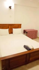 uma cama com uma cabeceira em madeira em Sobasee Deluxe Bungalow em Kandy