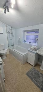 a bathroom with a tub and a toilet and a sink at Shrigley cottage, quirky & quiet in Macclesfield