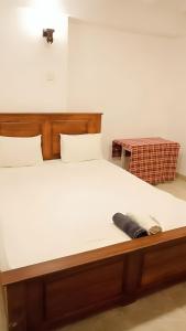 a bed with a wooden headboard and white sheets at Sobasee Deluxe Bungalow in Kandy