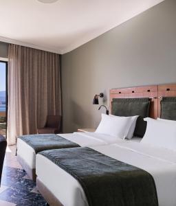2 letti in una camera d'albergo con finestra di Kalamaki Beach Resort a Isthmia