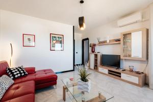 een woonkamer met een rode bank en een tv bij Casa Nilla in Monopoli
