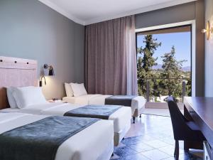 Habitación de hotel con 2 camas y escritorio en Kalamaki Beach Resort, en Istmia