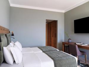 a bedroom with a bed and a desk and a television at Kalamaki Beach Resort in Isthmia