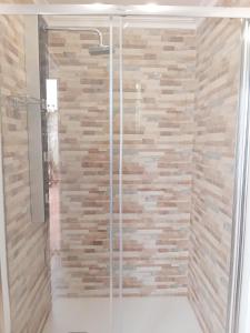 eine Dusche mit einer Glastür und einer Steinmauer in der Unterkunft Casa Elena in Orba