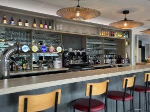 a bar with three chairs and a counter with drinks at ibis Laon in Laon