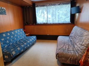 a room with a couch and a chair and a window at Studio Mont dore proche funiculaire in Mont-Dore