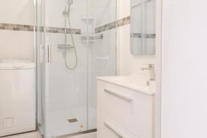 Un baño blanco con ducha y lavabo. en Grand studio face mer Les Sables d'Olonne 4 personnes, en Les Sables-dʼOlonne
