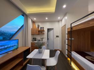 een slaapkamer met een bed en een bureau met een televisie bij Hanoi Amsterdam Condotel in Da Lat