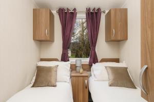 two beds in a room with purple curtains at BUNNY - 3 Bed Static Caravan in Port Seton