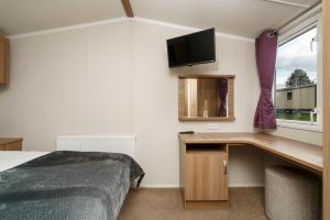 Schlafzimmer mit einem Bett, einem Schreibtisch und einem Fenster in der Unterkunft BUNNY - 3 Bed Static Caravan in Port Seton