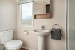 a white bathroom with a toilet and a sink at BUNNY - 3 Bed Static Caravan in Port Seton
