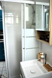 La salle de bains est pourvue d'un lavabo blanc et d'une douche. dans l'établissement La petite Marie-B, terrasse, plages à 250m, à Luc-sur-Mer
