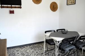 une table et des chaises dans une pièce dotée d'un mur blanc dans l'établissement La petite Marie-B, terrasse, plages à 250m, à Luc-sur-Mer