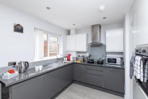 a kitchen with gray counters and white cabinets at Leeds 3 Bed - Parking, Self Check-in, En-suite, WiFi, Fussball, Garden - Groups, Contractors, Families, Long Stays - Alt-Stay in Bramley