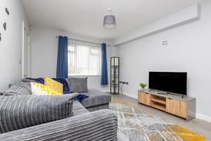 a living room with a couch and a flat screen tv at Leeds 3 Bed 2 - Off Road Parking, Self Check-in, Fast Wi-Fi, Table Football - Families, Contractors, Long Stays in Bramley
