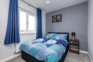 um quarto com uma cama com cortinas azuis e uma janela em Leeds 3 Bed - Parking, Self Check-in, En-suite, WiFi, Fussball, Garden - Groups, Contractors, Families, Long Stays - Alt-Stay em Bramley