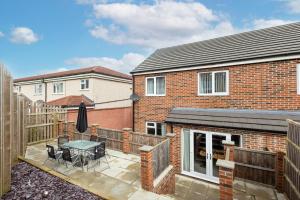 a brick house with a patio with a table and chairs at Leeds 3 Bed 2 - Off Road Parking, Self Check-in, Fast Wi-Fi, Table Football - Families, Contractors, Long Stays in Bramley