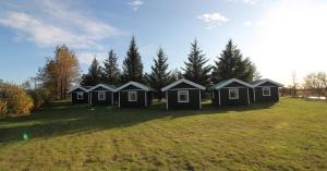 a row of black houses in a field at Arhus Cottage and Camping in Hella