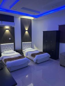 two beds in a room with blue lights at Dar Al Karama Residential Units in AlUla +11 photos