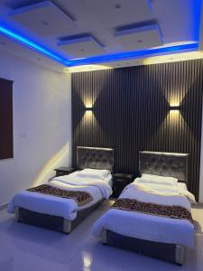 two beds in a hotel room with blue lights at Dar Al Karama Residential Units in AlUla