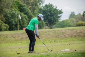a woman is playing golf on a golf course at Embogo Safari Lodges in Katoke