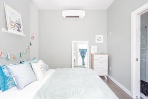 a white bedroom with a white bed with blue pillows at Pastel Paradise - Adorable Covington Apartment in Covington