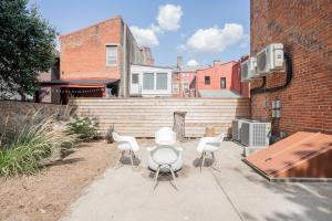 un patio con sillas blancas y una mesa y un edificio en Pastel Paradise - Adorable Covington Apartment, en Covington