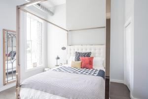 Dormitorio blanco con cama con dosel y almohadas rojas en Cute & Cozy - Perfect for Business or Leisure, en Covington