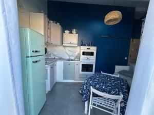 a small kitchen with a table and a blue wall at Studio bord de mer 1 lit double 1 lit simple in Hyères
