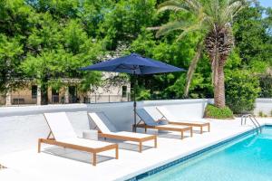 a group of chairs and an umbrella next to a swimming pool at Church St Collection - 109 Whole House and Pool in Fairhope