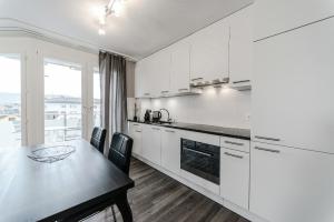 a kitchen with white cabinets and a table with chairs at RELOC Serviced Apartments Zurich-Oerlikon in Zurich
