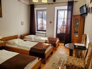 カームヤネツィ・ポジーリシクィイにあるHetman Hotelのベッド3台、テーブル、窓が備わる客室です。