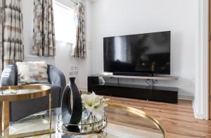 uma sala de estar com uma televisão e uma mesa de vidro em THE RISE - A beautiful 2 bedroom house, only 17mins to Central London!!! em Northfleet