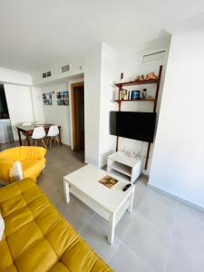 uma sala de estar com um sofá amarelo e uma mesa em Apartamento en primera línea con vistas a la playa Ensenada del Esparto del Residencial Viña del Mar em La Manga del Mar Menor