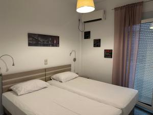 two twin beds in a room with a window at Renovated flat with Acropolis view in Athens