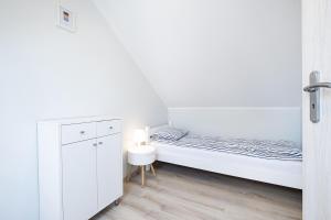 a white bedroom with a bed and a cabinet at Bedroom - domek nr 1 in Łeba